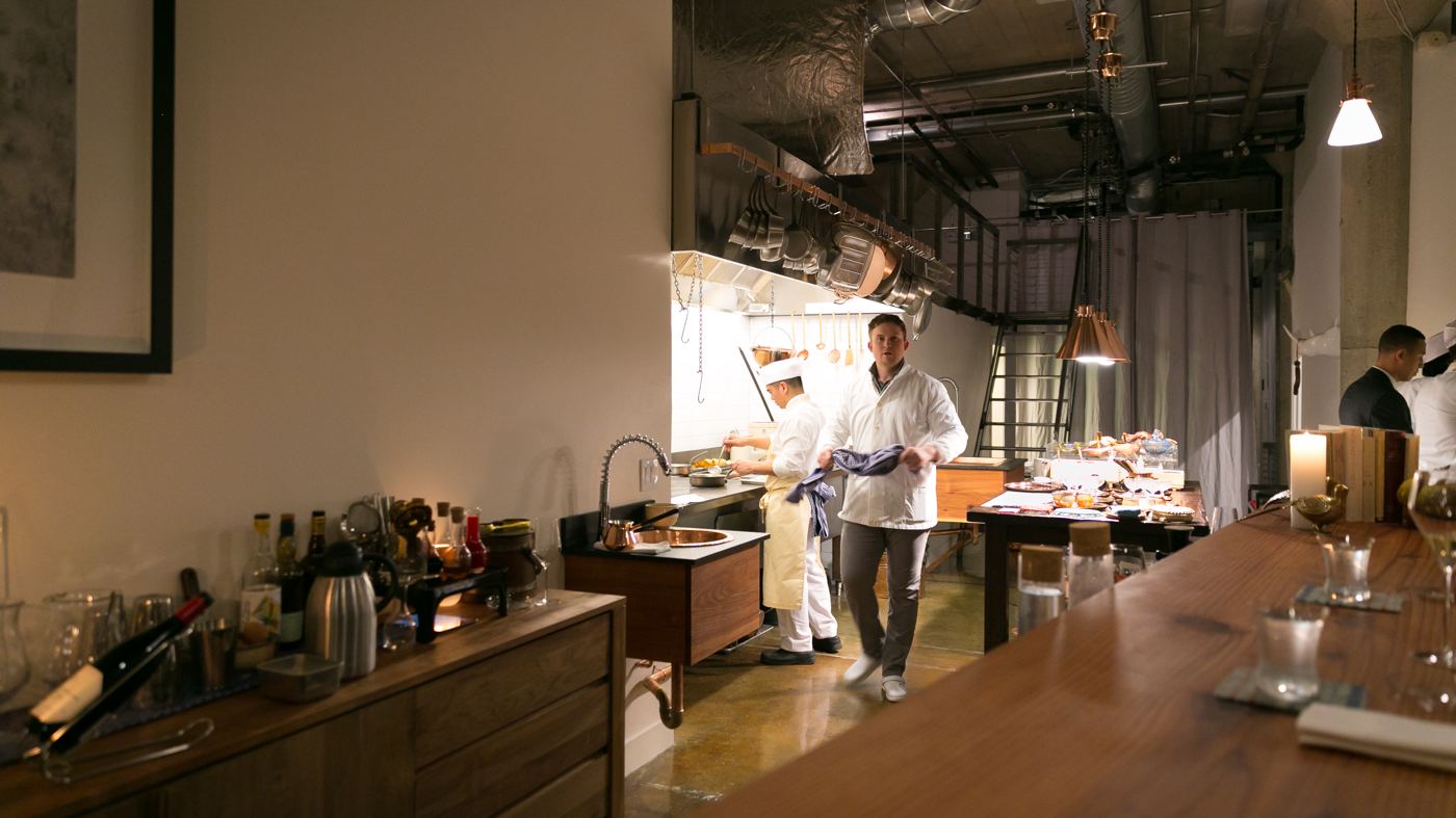 A restaurant's open kitchen and counter, a cook at work